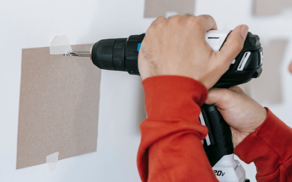 Close-up of a cordless drill fixing a bracket to a wall
