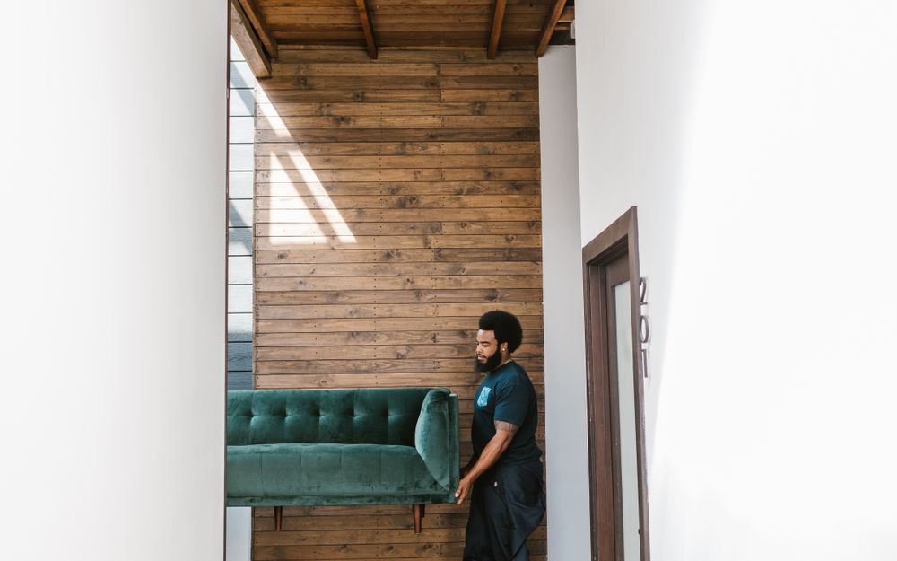 A removalist carrying a lounge through a hallway
